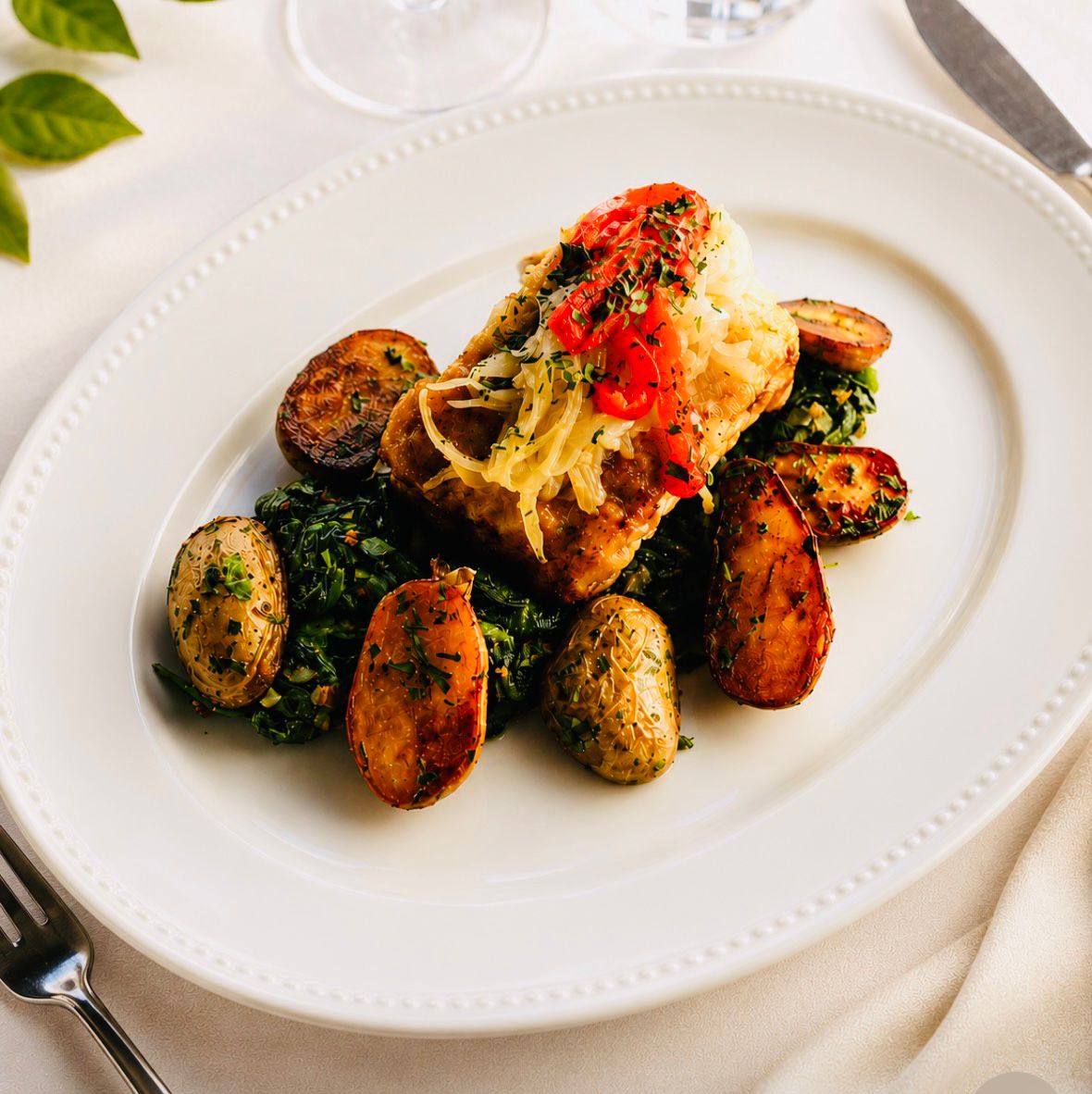 Lombo de peixe sobre espinafres com batatas salteadas e pimentos